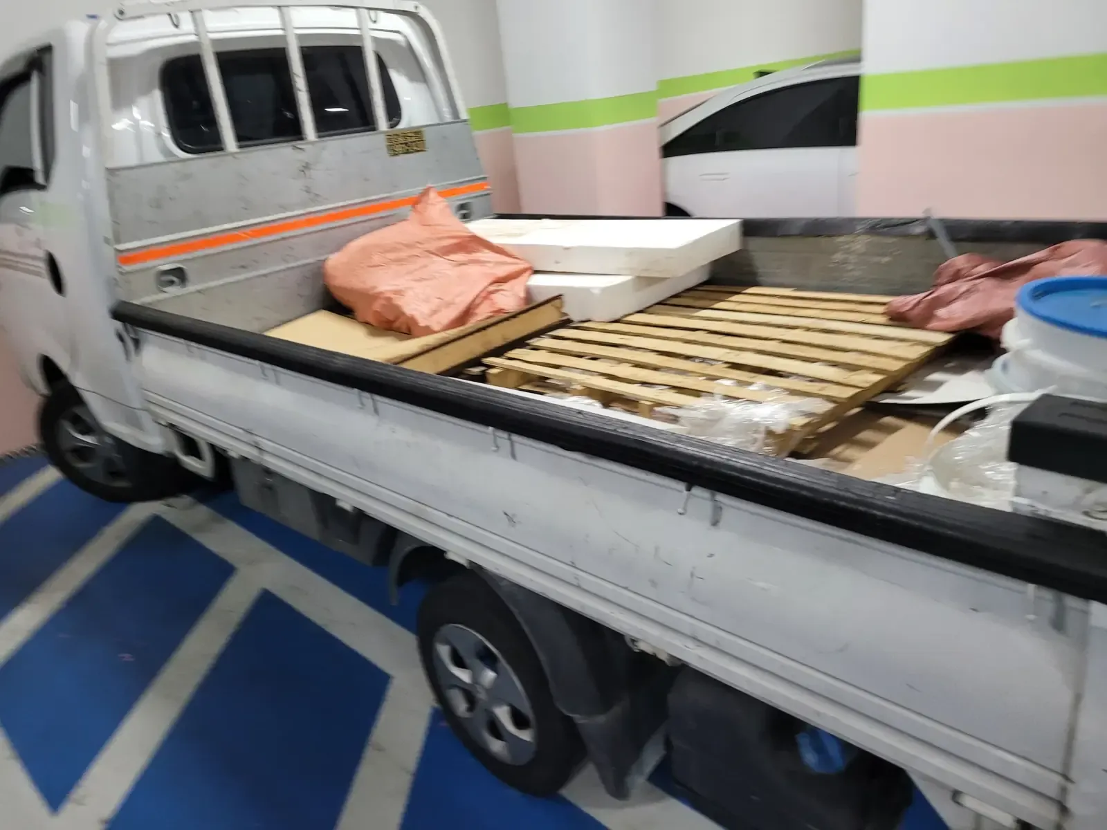 트럭 적재함에 목재 팔레트와 보드, 마대가 실려 있는 목재폐기물 수거 모습