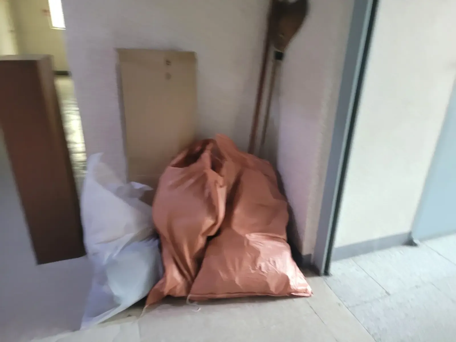 문 옆에 목재 판재와 주황색 마대가 놓여 있는 목재폐기물 현장